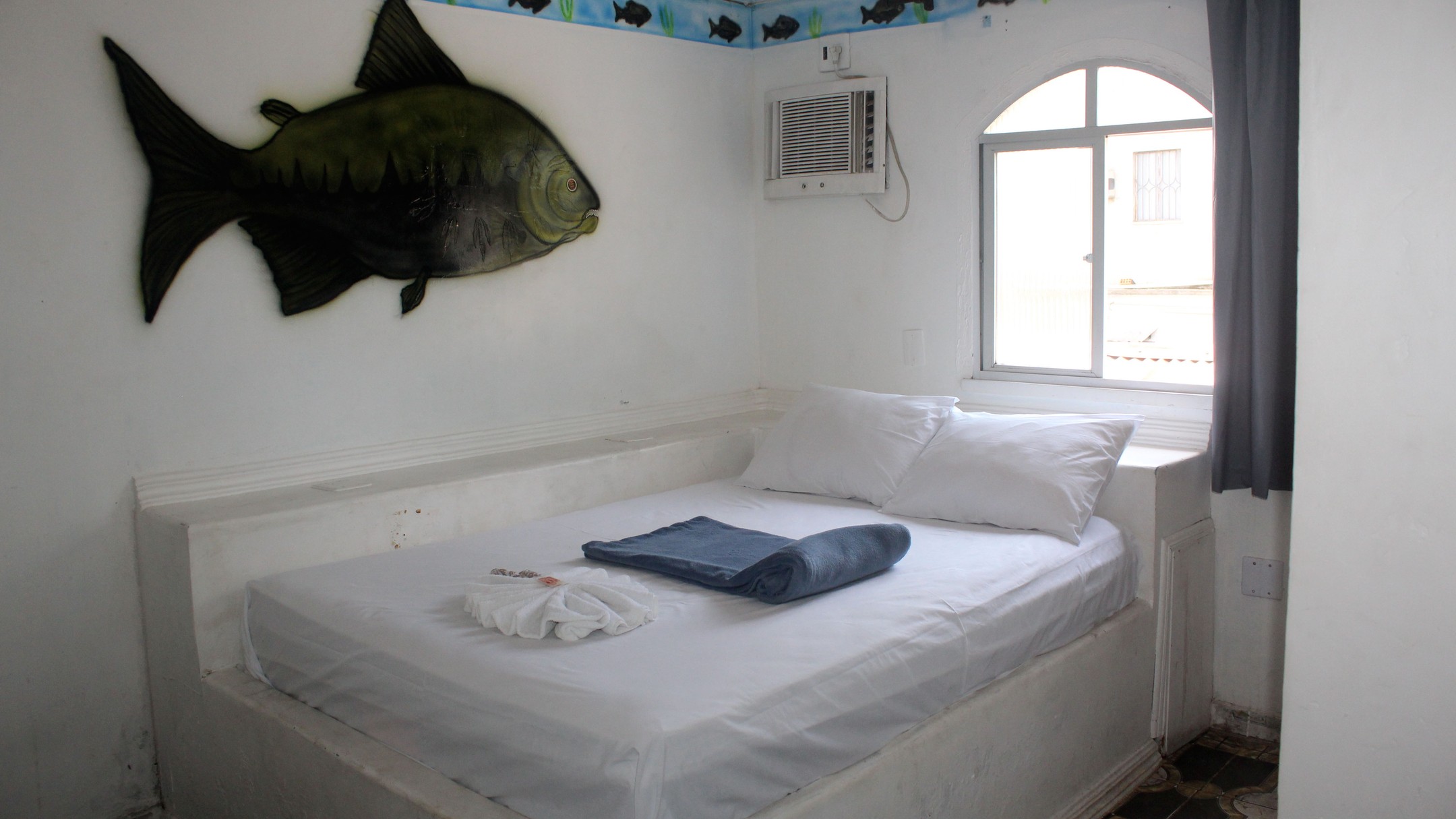 Quarto Tambaqui com mural de peixe e janela iluminada